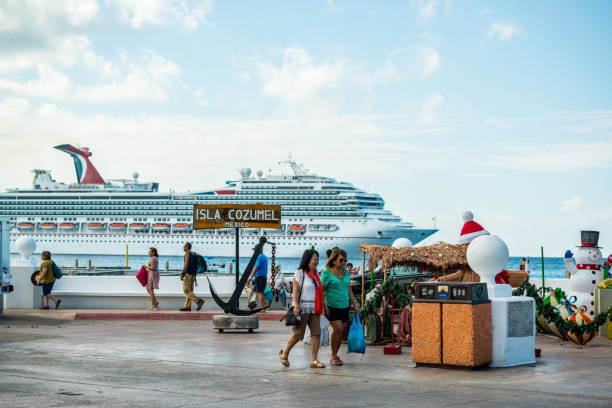 Cozumel, Mexico - December 29, 2016: Tourists exploring Cozumel Island during winter holidays. Christmas decorations and Cruise Ship Carnival Freedom on background.