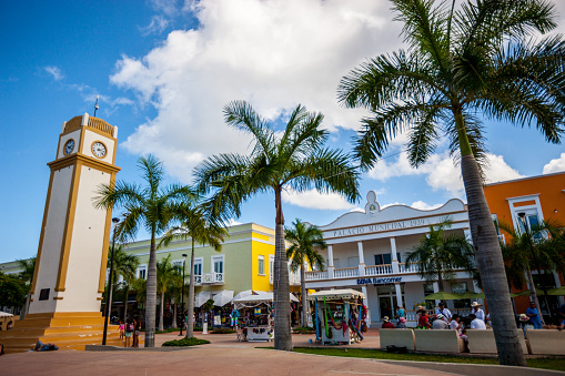 Cozumel, Mexico - December 29, 2016: Cozumel main square with clock tower, bank and municipality, people relaxing outdoors