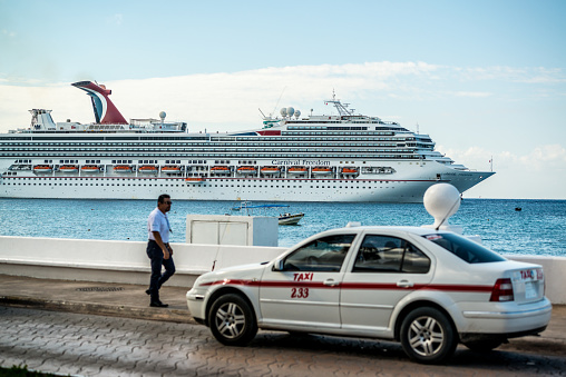 Cozumel, Mexico - December 29, 2016:  Taxis parked on Cozumel street, waiting for tourists. Cruise ship on background.