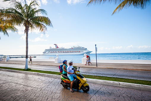 Cozumel, Mexico - December 29, 2016: People on motorcycles on Cozumel street with cruise ship on background, Mexico