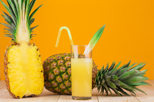 Half of Fresh ripe pineapple and juice. Located on the wooden background.