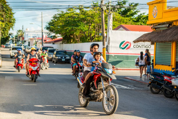 Cozumel, Mexico - December 29, 2016: People on motorcycles on Cozumel street with cruise ship on background, Mexico. Man with little boy on foreground