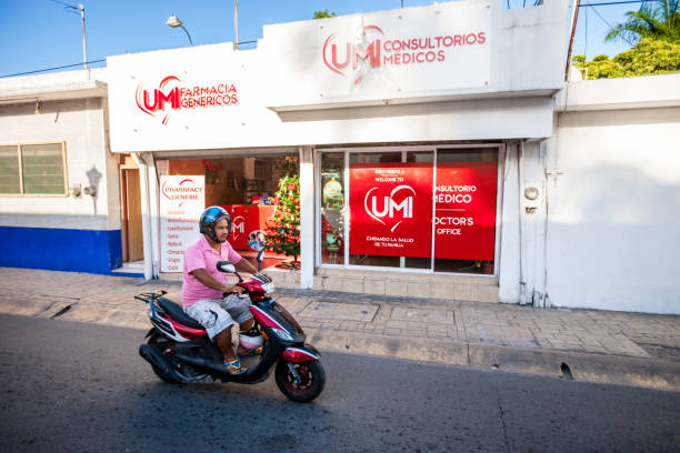 Cozumel, Mexico - December 29, 2016: Man on motorcycle on Cozumel street with cruise ship on background, Mexico. Medical clinic on background