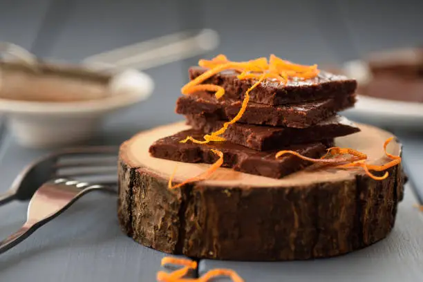 Healthy craft chocolate bars with orange rind on wood slabs closeup selective focus
