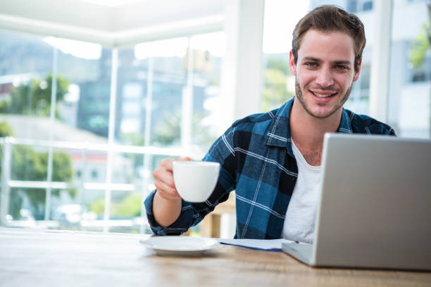 istock Handsome man working on laptop with cup of coffee 701032232