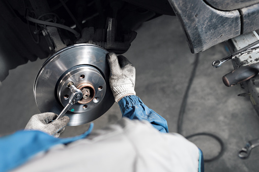 Car mechanic hands replace brakes in garage. Mechanic technician worker installing car wheel at maintenance. Worker changing brake disc. Brake disc installation concept. - can use to display or montage product or make a website for service