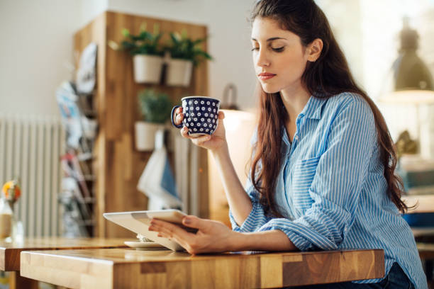 istock Woman holding coffee cup and tablet pc in cafe 701036430