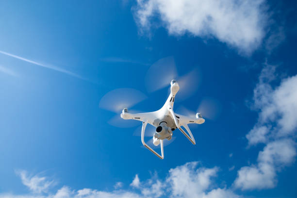 mouche de drone dans le ciel bleu - survoler photos et images de collection