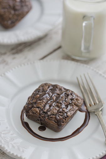 Single Chocoate Brownie on Plate with a glass of milk