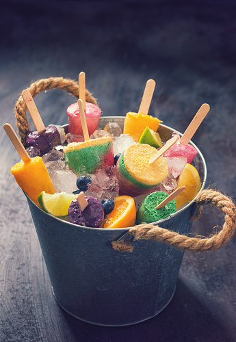 Fresh homemade fruit popsicles in the bucket with ice
