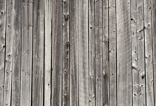 Wooden planks exposed to the weather nailed to make either a deck floor or a fence.