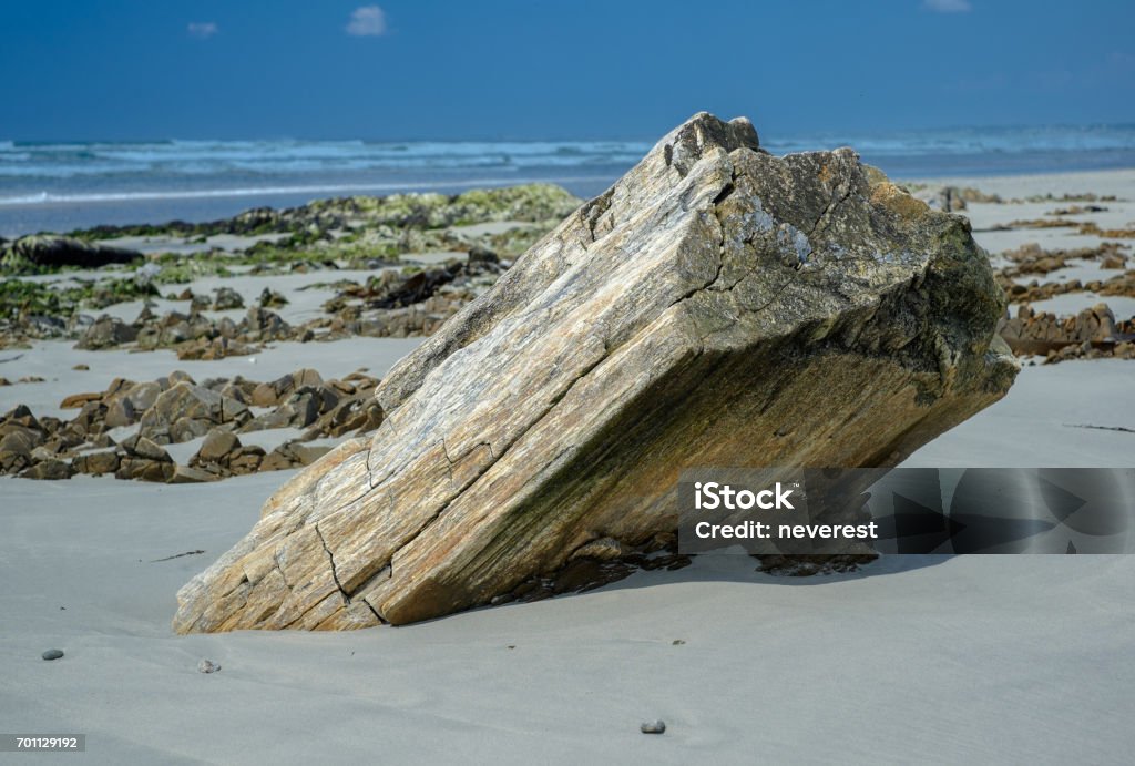 Slanted rock wave beaten rock on a sandy beach Beaten Up Stock Photo