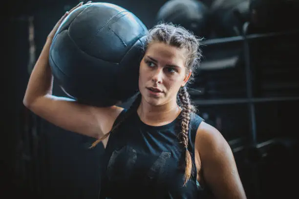 Athlete woman in gym practicing cross training with medicine ball