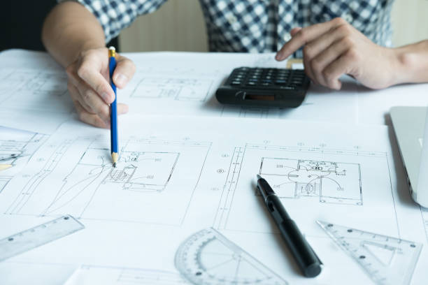 istock Architect working on real estate project at workplace. Male engineer hand working with living house blueprint at office. Business, people, construction and building concept 701152314