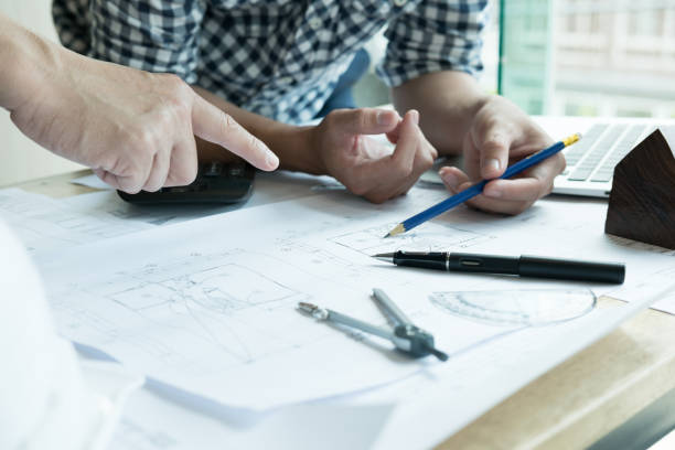 istock Architect working on real estate project with partner at workplace. Male engineer hand discussing with colleague on living house blueprint at office. Business, people, construction and building concept 701152328