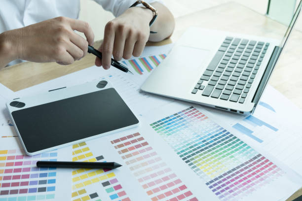 istock young graphic designer working with computer and color swatch. creative man using stylus pen and digital tablet at modern office. Architect using work tools and sample colour catalog. business, technology, design and people concept 701152384