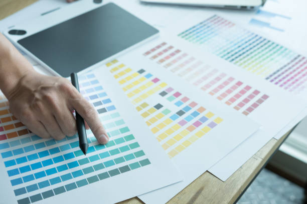 istock young graphic designer working with computer and color swatch. creative man using stylus pen and digital tablet at modern office. Architect using work tools and sample colour catalog. business, technology, design and people concept 701152434
