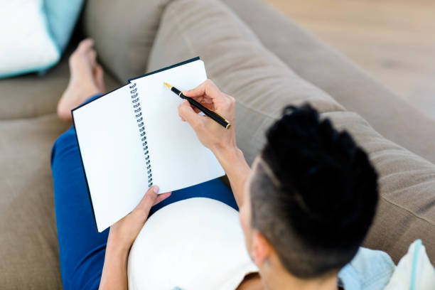 istock Pregnant woman writing on notepad 701162450