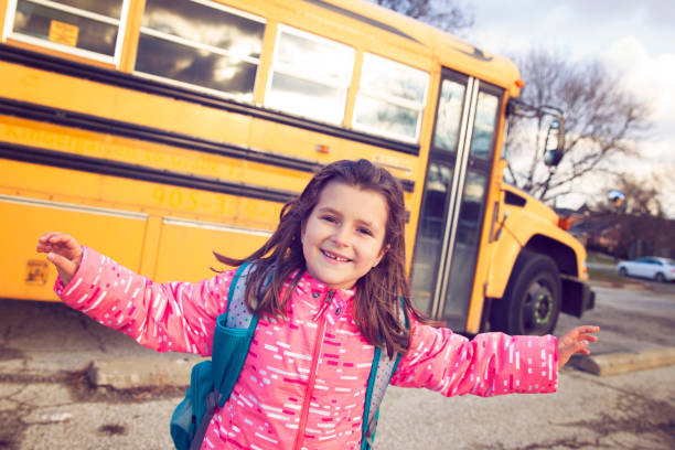 istock Girl Infront of a School Bus 701184280
