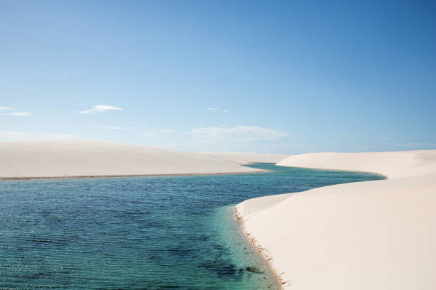 River-shaped lagoon among white sand dunes stock photo