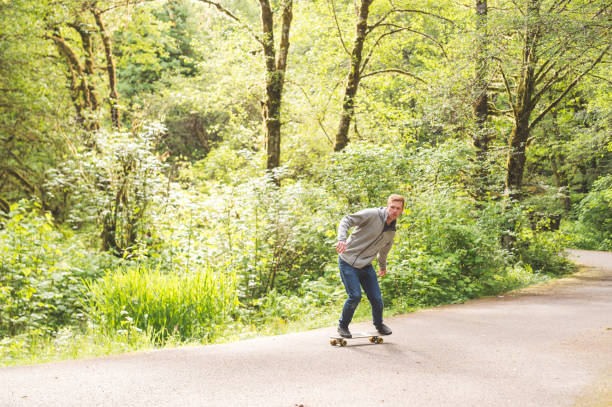 red-haired male skateboards through forest - hat trick imagens e fotografias de stock