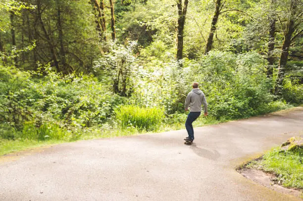 Red-haired male skateboards through forest and tries some tricks out