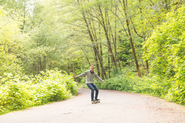 istock Red-haired male skateboards through forest 701198382