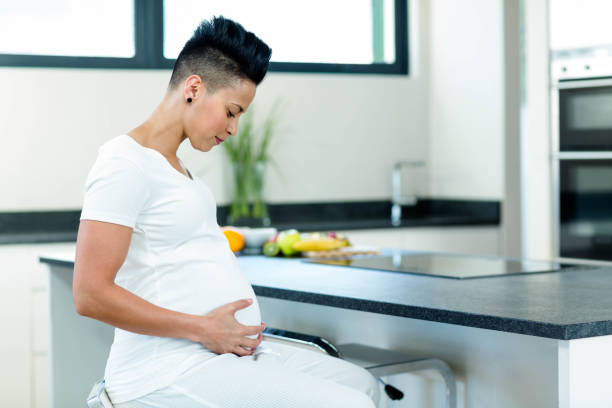 istock Pregnant woman sitting near kitchen worktop 701209954