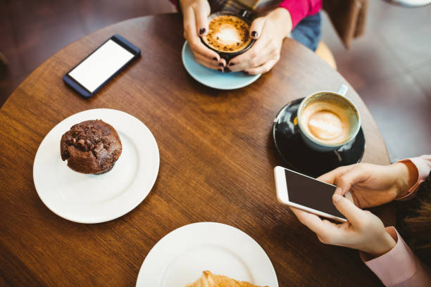 amici che usano il loro smartphone - coffee muffin pastry blueberry muffin foto e immagini stock