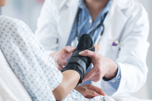 healthcare professional places brace on patient's arm - sprain imagens e fotografias de stock