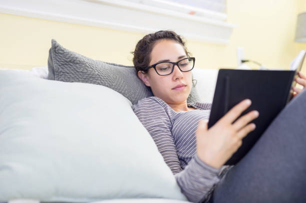 istock Attractive young Hispanic woman on bed reading journal 701234002