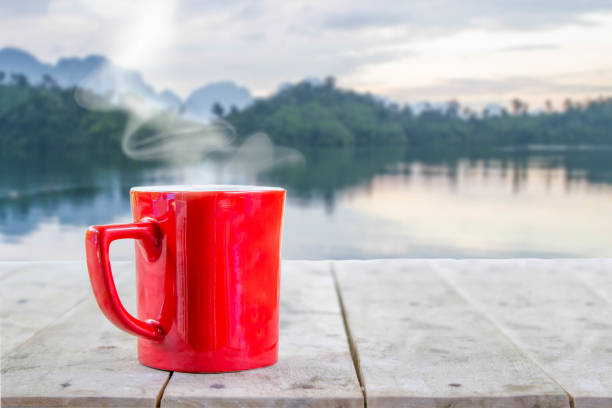 istock hot coffee with white smoke in red  cup on wood table 701257608