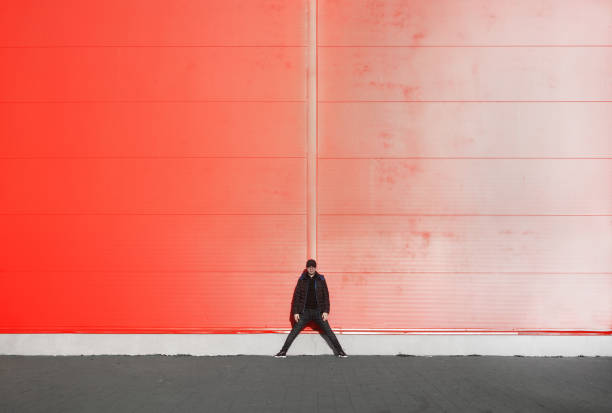 istock Full Length Of Man Standing Against Orange Wall 709181637