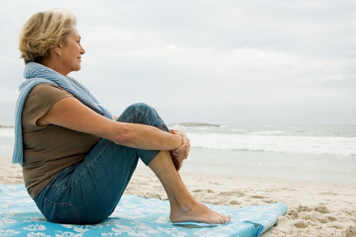 Senior adult woman sat on the beach