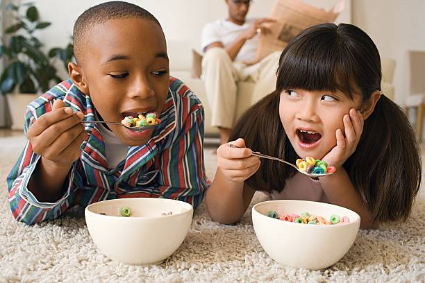 Boy and girl lying in living room eating cereal  boys bowl haircut stock pictures, royalty-free photos & images