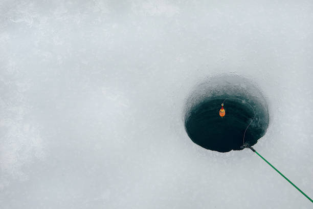 High Angle View Of Fishing Rod Over Hole In Frozen Lake  ice fishing stock pictures, royalty-free photos & images