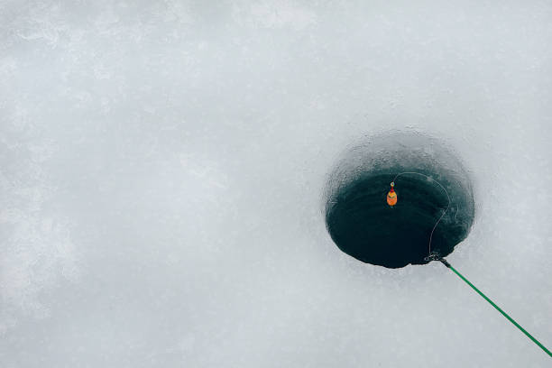 вид под большим углом на удочку над лункой в замерзшем озере - ice fishing стоковые фото и изображения