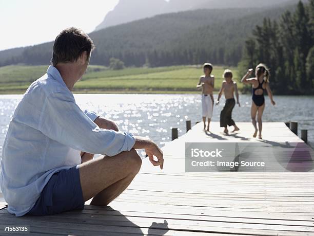 Padre Guardando I Bambini Giocare - Fotografie stock e altre immagini di Adulto - Adulto, Albero, Ambientazione esterna