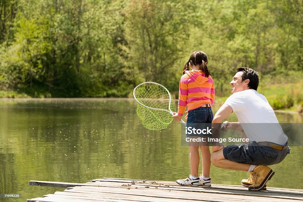 Отец присесть рядом с дочь на пристани, держит рыболовная сеть - Стоковые фото Девочки роялти-фри