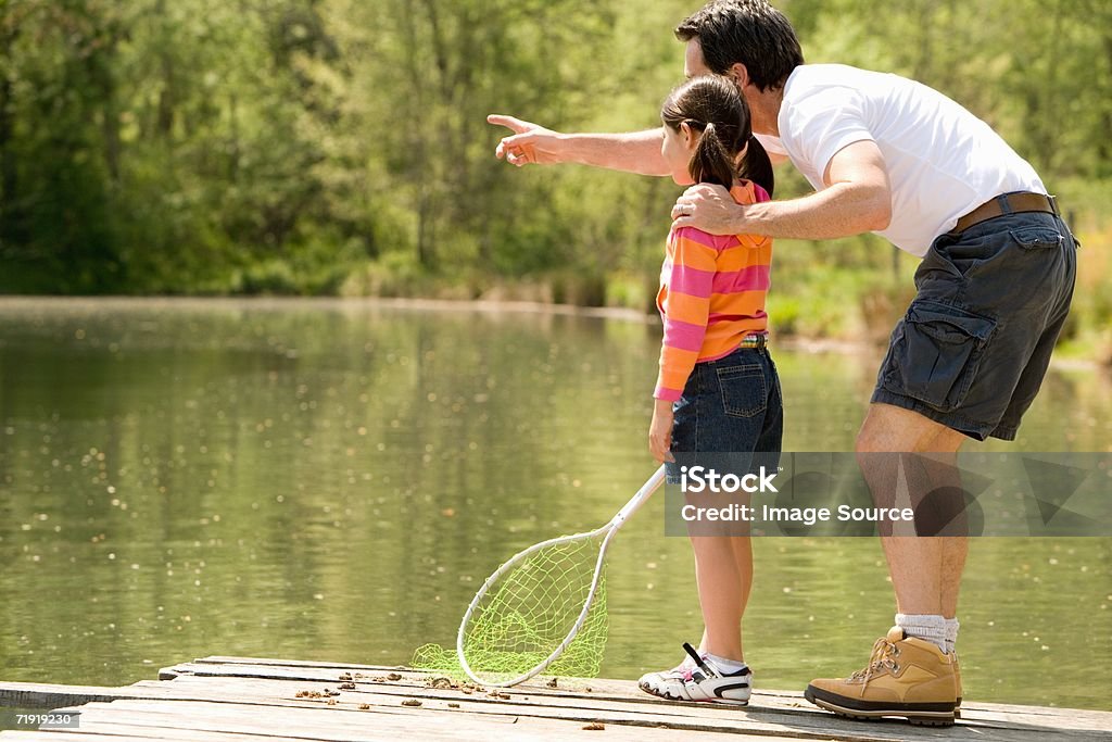 Father and daughter on jetty, holding fishing net - Foto de stock de 30 Anos royalty-free
