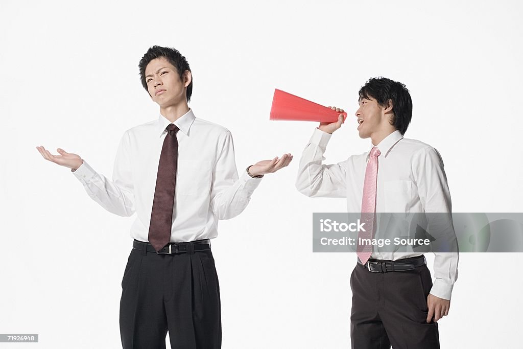 Man shouting at colleague with megaphone - Foto stock royalty-free di Giappone