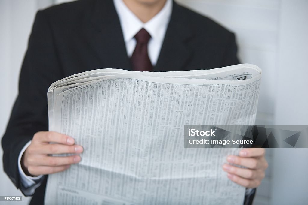 Empresário lendo um jornal volante - Foto de stock de Jornal royalty-free