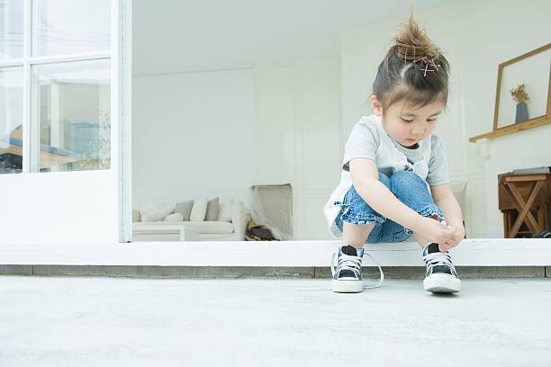 여자아이 학습 침목 자신의 신발끈 묶기 - 독립 뉴스 사진 이미지