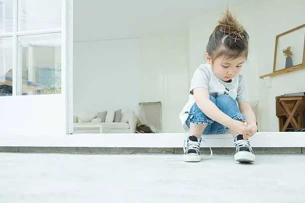 Photo of Girl learning to tie her shoelaces