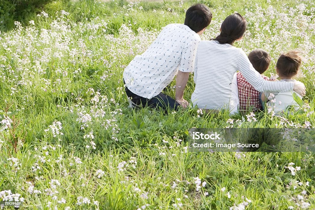Famiglia asiatica seduto in un campo - Foto stock royalty-free di Abbracciare una persona