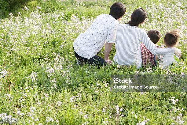 Famiglia Asiatica Seduto In Un Campo - Fotografie stock e altre immagini di Abbracciare una persona - Abbracciare una persona, Adulto, Ambientazione esterna