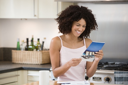 Sonriente mujer leyendo un folleto en la cocina photo