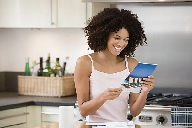 Photo of Smiling woman reading a brochure in kitchen