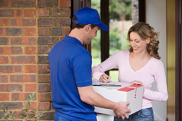 woman getting a parcel from delivery man - home delivery potret stok, foto, & gambar bebas royalti