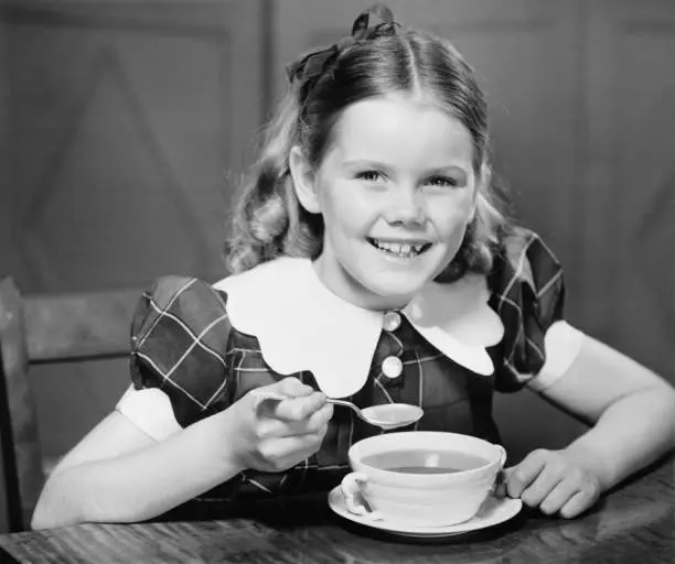 Photo of Girl (10-11) eating soup at table (B&W), portrait